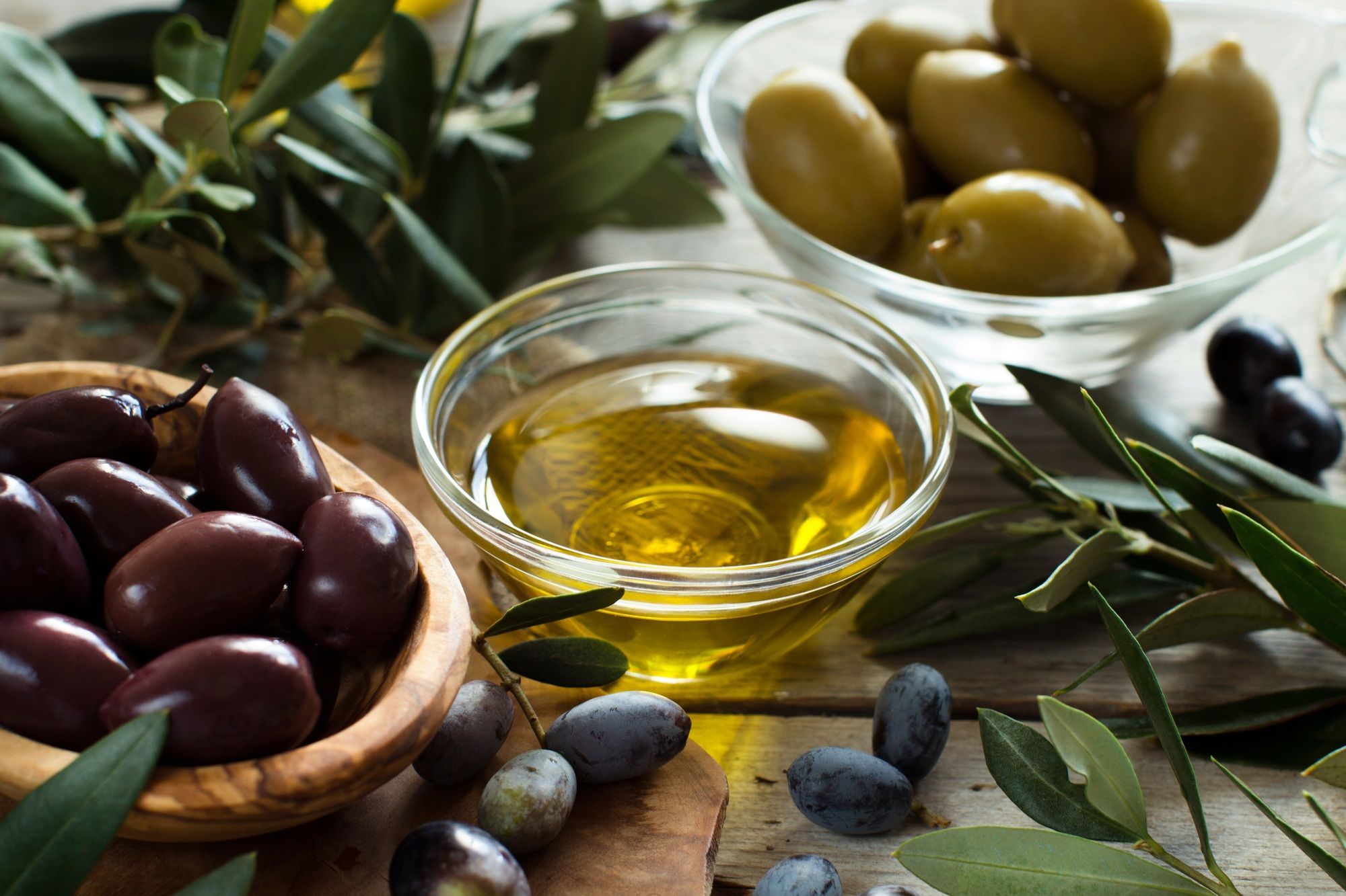 Olive oil and olives on wood background